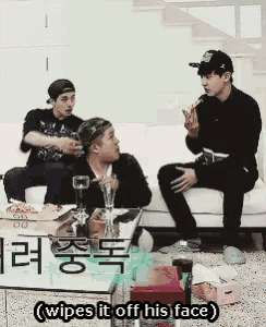 three men are sitting on a couch and one of them is eating pizza