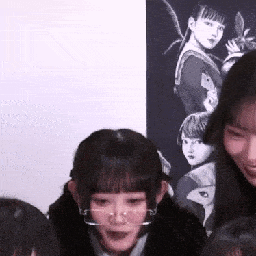 a girl wearing glasses is smiling in front of a poster of a girl