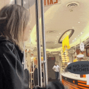 a woman stands in front of a store that has a sign that says no skill bitch