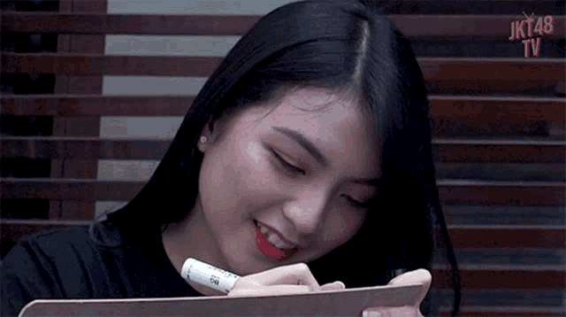 a girl is writing on a clipboard with a marker and smiling ..