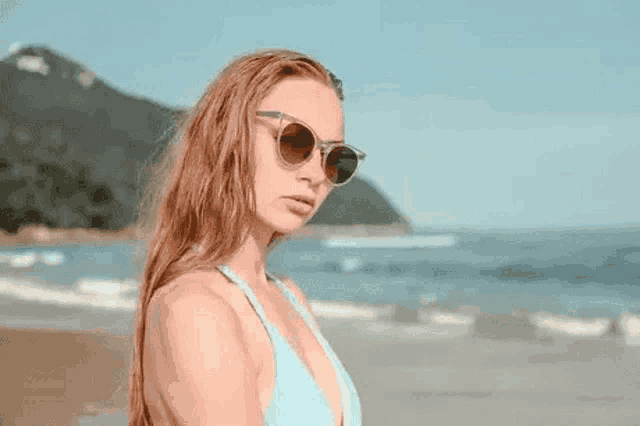 the woman is wearing sunglasses and a bikini on the beach .