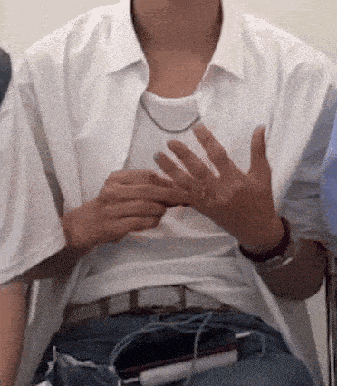 a man in a white shirt is sitting in a chair with his hands in his pockets .