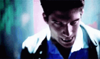 a man in a blue shirt and white jacket is looking at the camera with his mouth open .