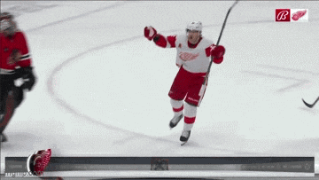 a hockey player in a red and white uniform with the letter b on the bottom