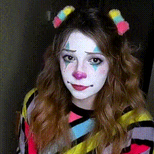 a girl is dressed as a clown and has a headband with pom poms in her hair .
