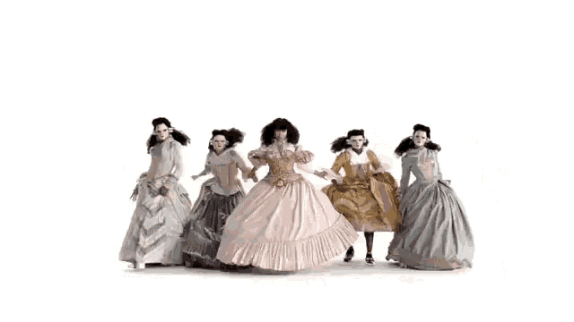 a group of women dressed in fancy dresses are standing in a row