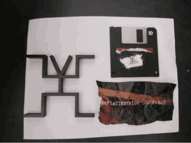 a floppy disk sits next to a piece of crumpled paper that says dmy