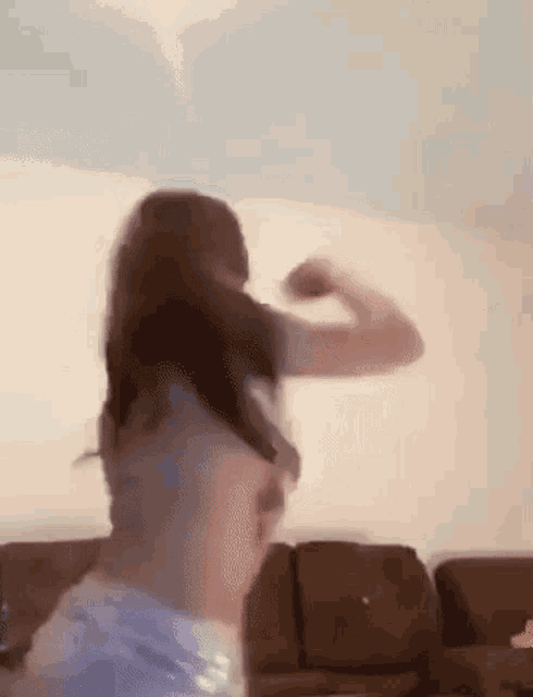 a woman is dancing in a living room with a couch .