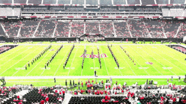 a marching band performs on a football field with the letters u.n.a. on the field