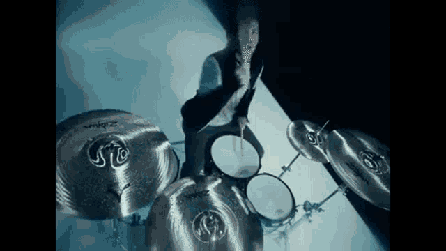 a man is playing drums in a dark room with a blue light behind him .