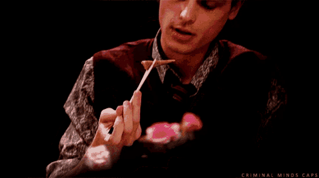 a close up of a man eating food with the words criminal minds caps visible