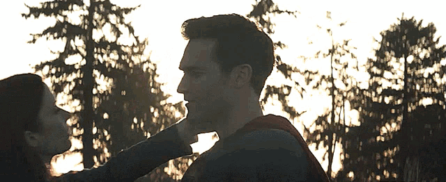 a man and a woman are looking at each other and the woman is touching the man 's face