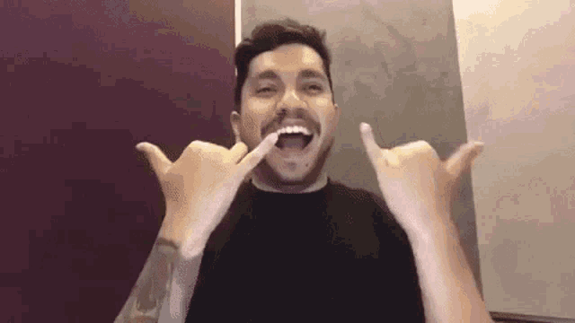 a man with a beard is making a funny face with his hands in front of his mouth .