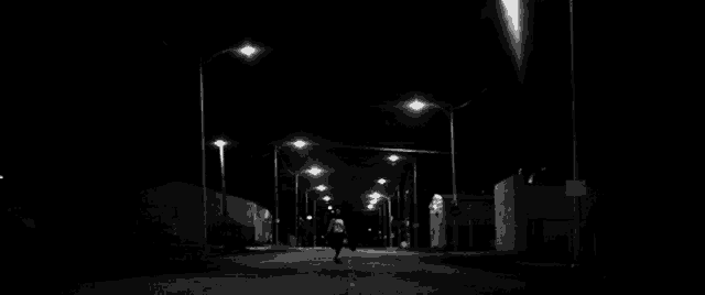 a black and white photo of a person holding a skateboard in their hand .