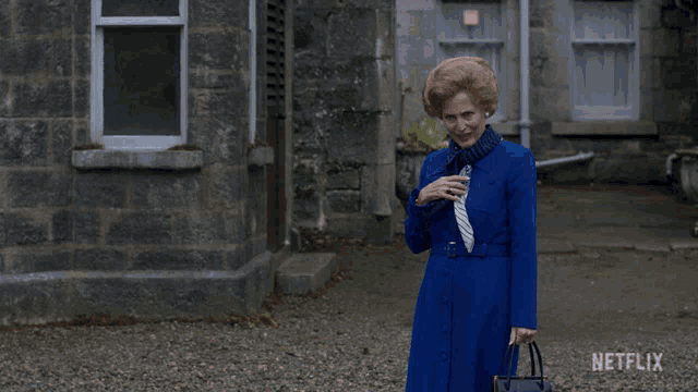 a woman in a blue coat and tie is standing in front of a netflix ad