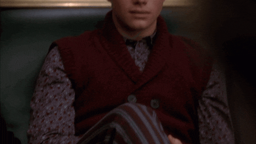 a man wearing a sweater vest and a floral shirt
