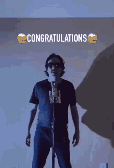 a man standing in front of a microphone with the words congratulations written above him