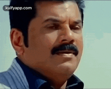 a man with a mustache is making a funny face and looking at the camera .