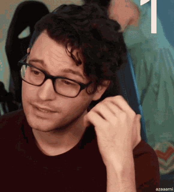 a man wearing glasses and a red shirt has the number 1 on the bottom