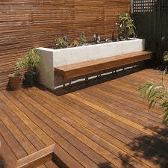 a wooden deck with a bench and a potted plant .