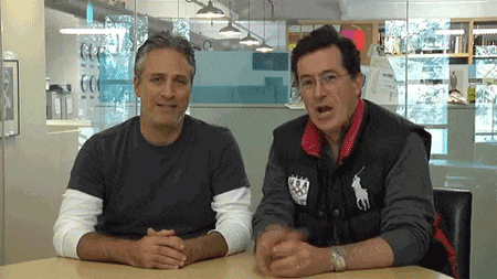 two men sitting at a table with one wearing a vest with a horse on it
