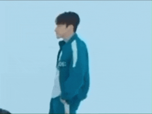 a man in a squid game uniform is standing in front of a blue background .