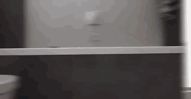 a person is standing in a bathroom next to a sink and a toilet .
