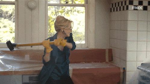 a woman is holding a hammer in a room with the word max on the wall