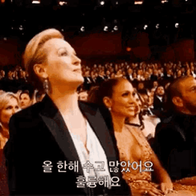 a woman in a suit is sitting in front of a crowd .