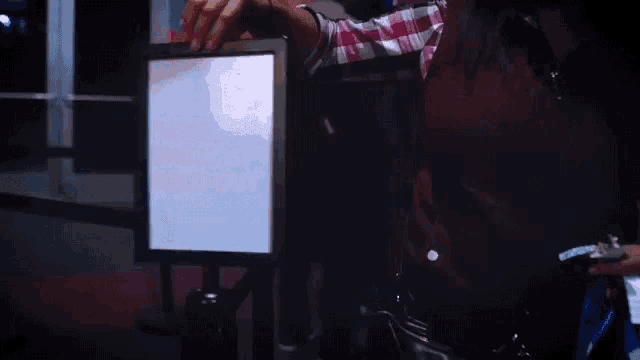 a person is holding a bottle of beer in front of a screen