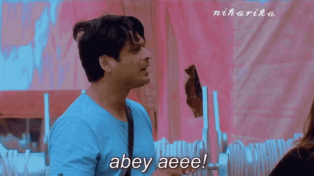 a man in a blue shirt says abey aeee on a pink background