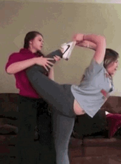 a woman is stretching her leg while another woman holds her leg up