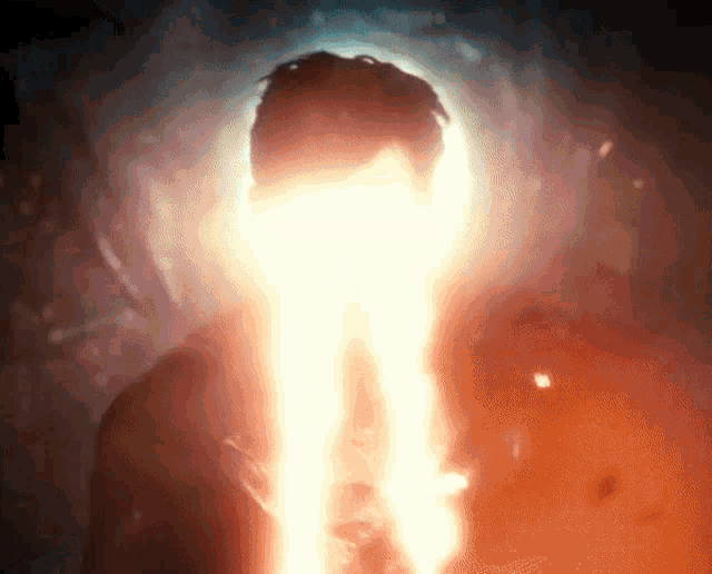 a man 's face is lit up by a bright light coming out of his mouth