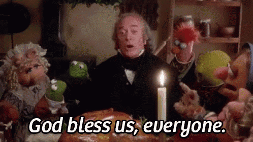 a group of muppets are sitting around a table with a candle and a man standing in front of them .