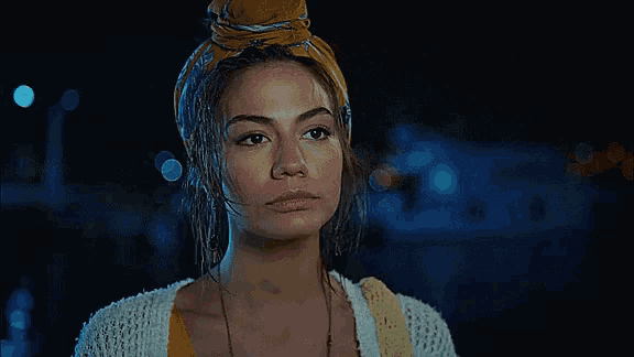 a woman wearing a yellow headband and a white sweater looks at the camera