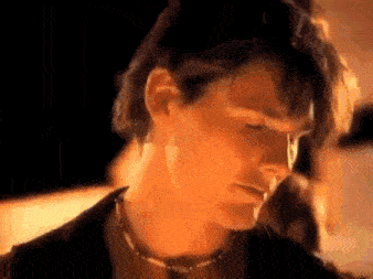 a close up of a man 's face wearing a choker necklace .