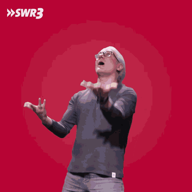 a man throws a stack of money in front of a red background with the letters swr3 on it