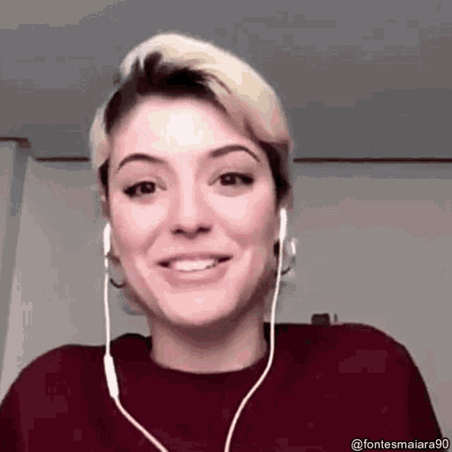 a woman wearing headphones is smiling while looking at the camera .