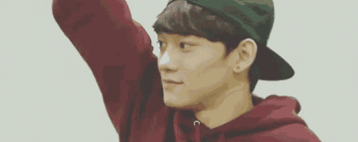 a young man wearing a green baseball cap and a red hoodie is standing with his arm up .