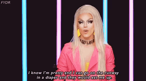 a drag queen is wearing a pink jacket and a choker while talking .
