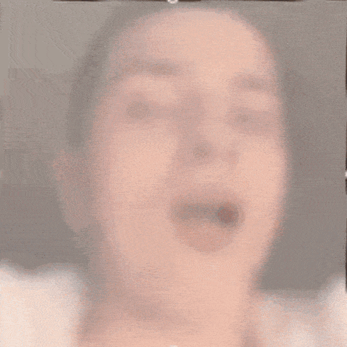 a close up of a woman 's face with her mouth open and her tongue sticking out .