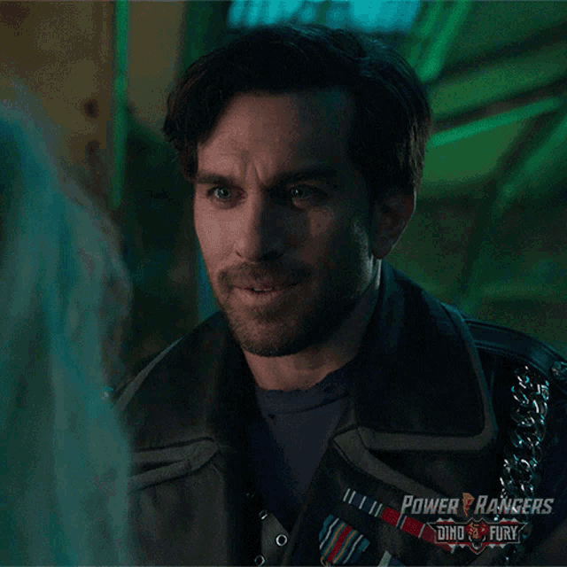 a man wearing a power rangers jacket smiles