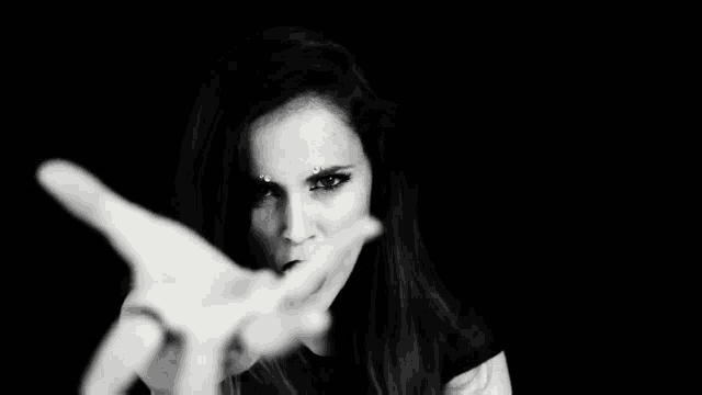 a woman is making a stop sign with her hand in front of her face in a black and white photo .