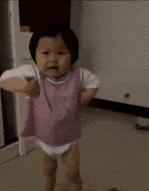 the baby is wearing a diaper and a purple shirt and is running .