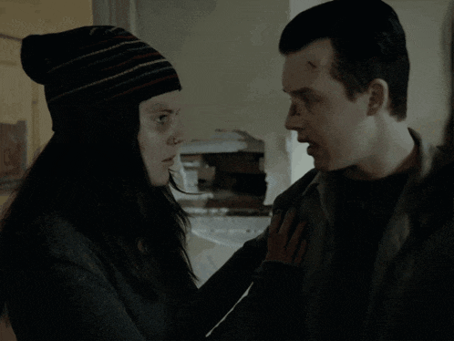 a man and a woman are looking at each other and the woman is wearing a striped hat