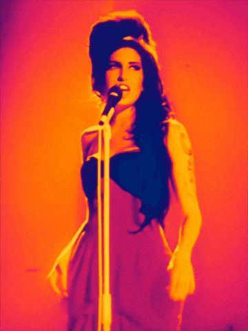 a woman in a red dress singing into a microphone with a colorful background