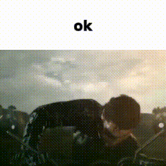 a man is laying on the ground in front of a cloudy sky with the word ok above him .