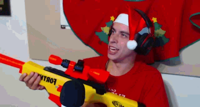 a man wearing a santa hat and headphones holds a nerf gun