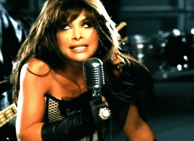 a woman is singing into a microphone in a dark room