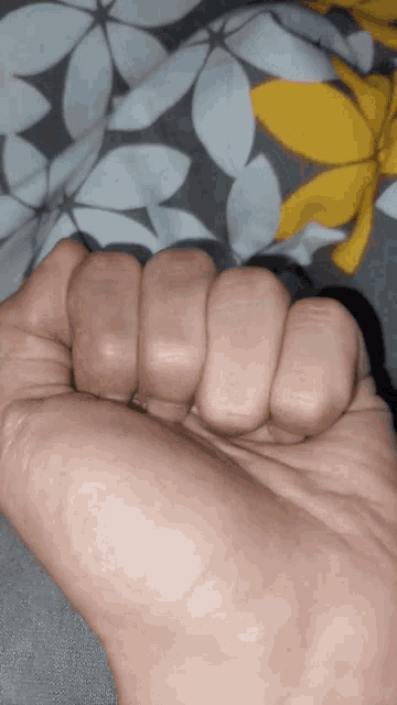 a close up of a person 's fist on a floral blanket